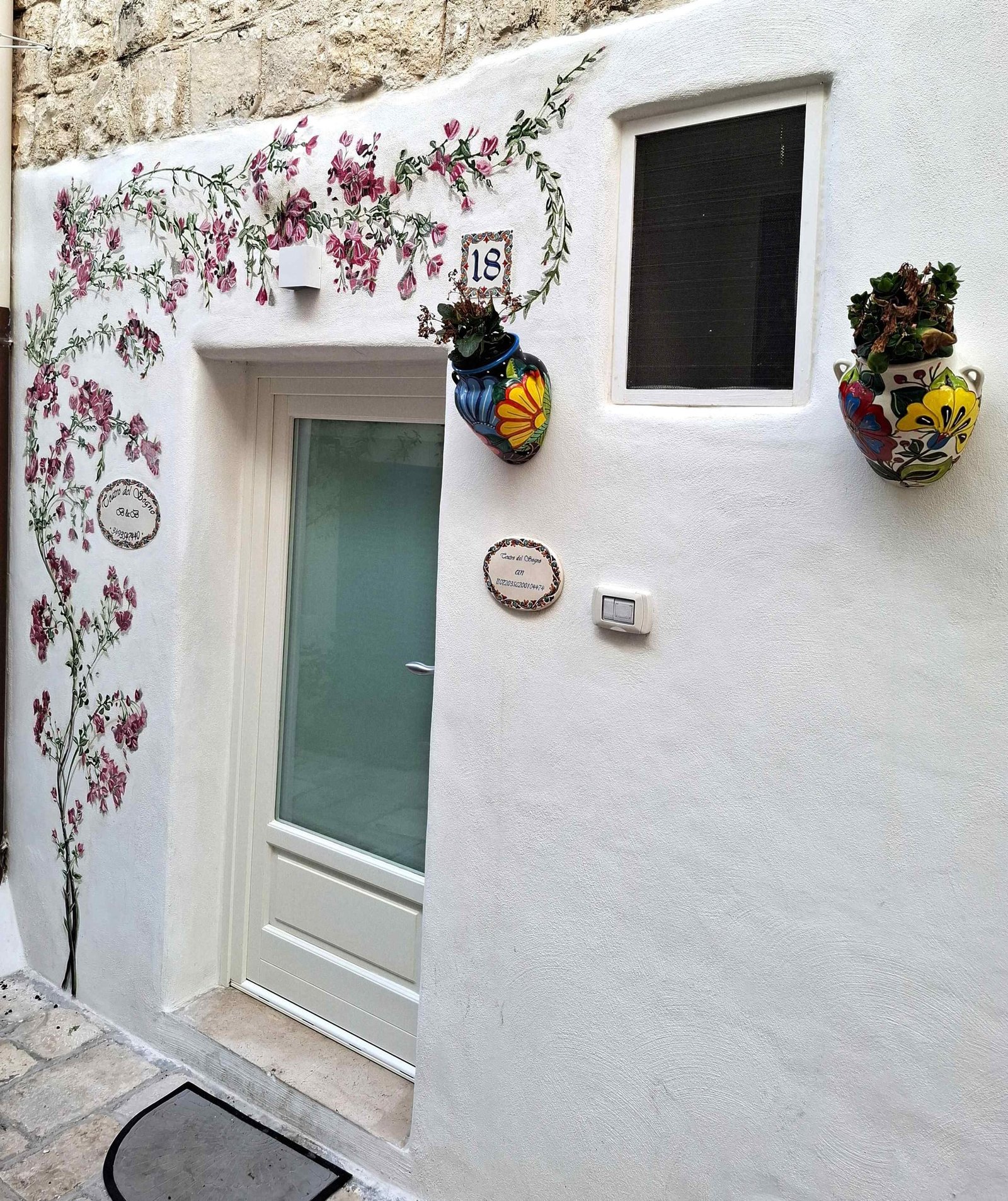 Zid pictat și decorațiuni tradiționale la poarta unei case din Polignano
